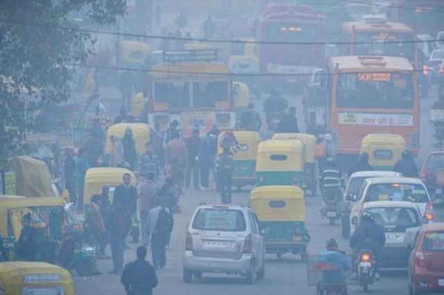 indian commuters travel on a polluted road near a bus terminus in the anand vihar district of new delhi on dec 18 2015 photo afp