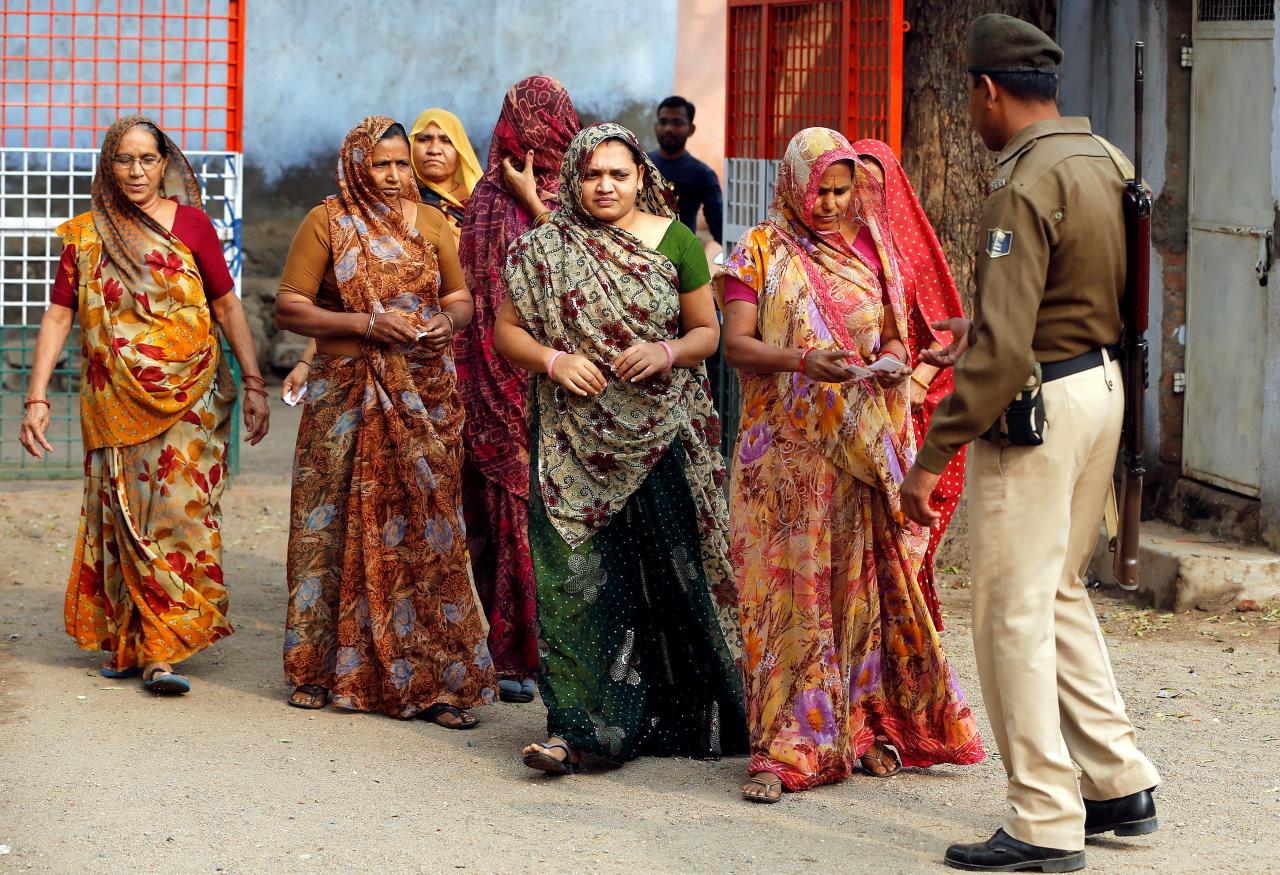 a policeman checks identity papers of women as they arrive to cast their votes at a polling station during the first phase of gujarat state assembly election in panshina village of surendranagar district photo reuters