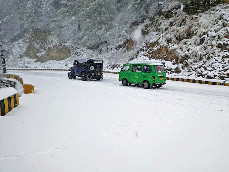 a man walks in rain in peshawar while a jeep pulls a van through snow in murree photo agencies