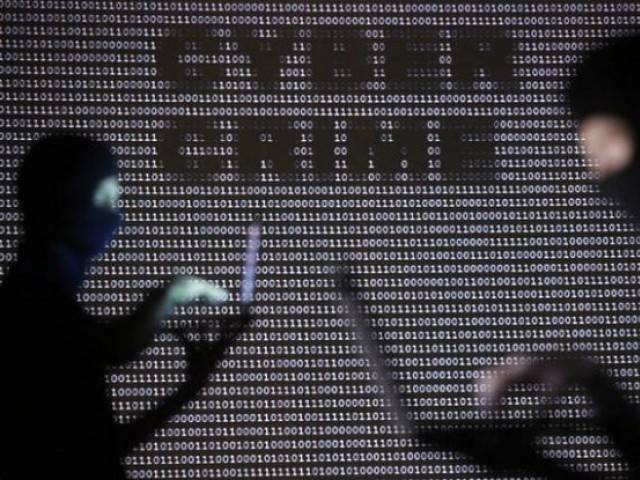 people wearing balaclavas are silhouetted as they pose with a laptops in front of a screen projected with the word 039 cyber crime 039 and binary code photo reuters
