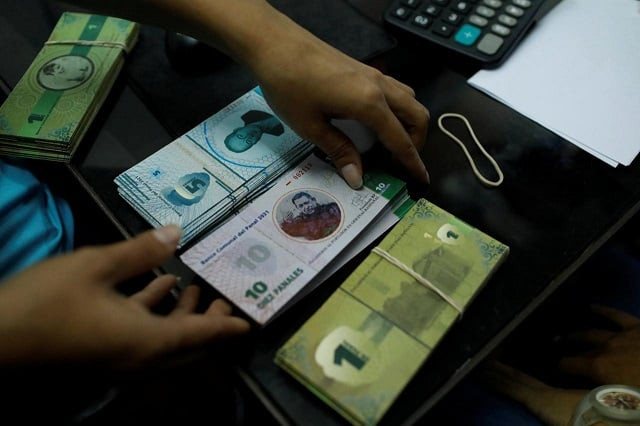 a cashier holds a stack of 10 panal notes depicting venezuela 039 s late president hugo chavez at a branch of banpanal communal bank in caracas venezuela december 15 2017 photo reuters a cashier holds a stack of 10 panal notes depicting venezuela 039 s late president hugo chavez at a branch of banpanal communal bank in caracas venezuela december 15 2017 photo reuters