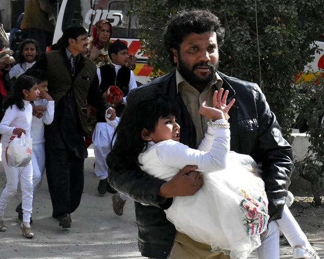 a man carries a girl as he runs out with others after gunmen attacked the bethel memorial methodist church in quetta december 17 2017 photo reuters