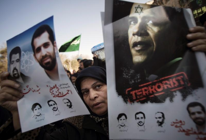 a worshipper holds an anti u s president barack obama poster and portraits of killed iranian nuclear scientists during the funeral for nuclear scientist mostafa ahmadi roshan who was killed in a bomb blast in tehran photo reuters