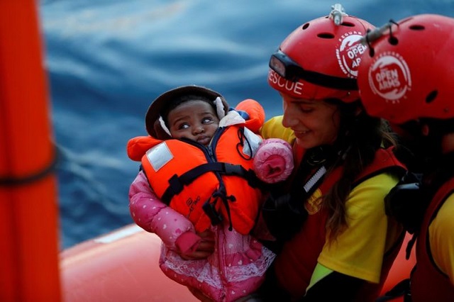 a crew member of mv open arms the search and rescue ship of proactiva open arms carries a migrant baby before passing it to crew members of mv aquarius a search and rescue ship run in partnership between sos mediterranee and medecins sans frontieres during a mid sea transfer of migrants in the central mediterranean off the coast of libya december 16 2017 photo reuters