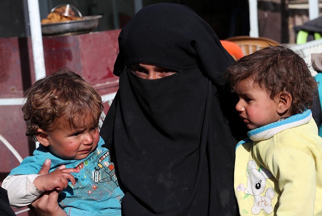 a syrian woman and her children wait for food aid in front of an humanitarian aid distrubition center in syrian border town of jarablus syria december 13 2017 photo reuters