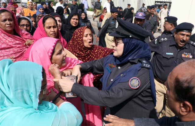 a female police officer tying to stop the protesting lady health workers photo online