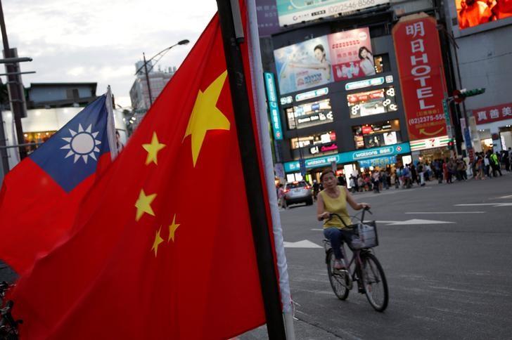 a woman rides a bike past taiwan and china national flags during a rally held in taipei taiwan photo reuters