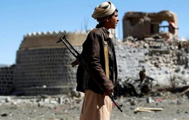 an armed yemeni inspects the damage following a reported saudi led coalition air strike on south sanaa photo afp