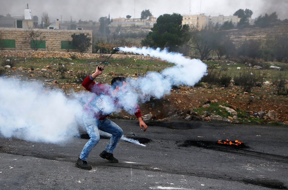 a palestinian man throws a tear gas canister back towards israeli security forces during clashes following the weekly muslim friday prayers in the west bank city of ramallah on december 29 2017 photo afp