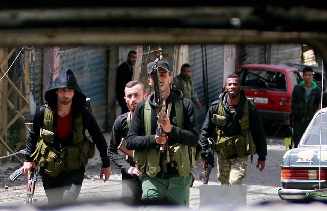 file photo members of the palestinian fatah faction walk with their weapons as seen through a damaged car inside the ain el hilweh refugee camp near sidon southern lebanon april 11 2017 photo reuters