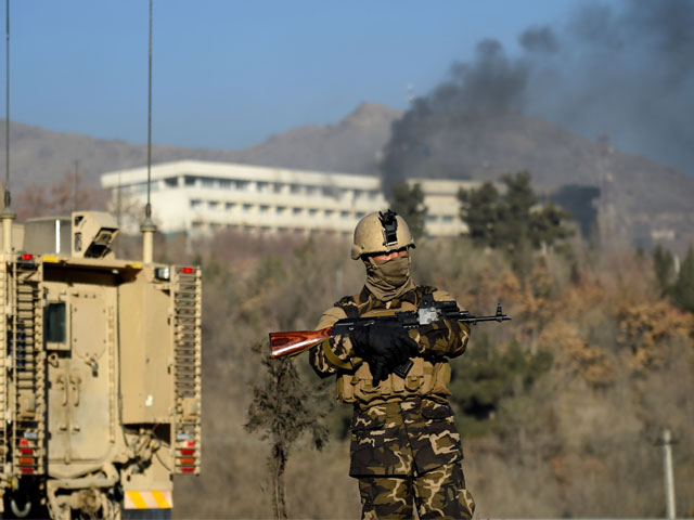 an afghan security personnel stands guard as smoke billows from the intercontinental hotel during a fight between gunmen and afghan security forces in kabul on january 21 2018 photo afp