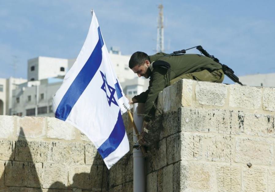 an israeli solider removes the flag from a rooftop in hebron as troops force jewish settlers out of homes they said they had purchased from palestinians photo reuters