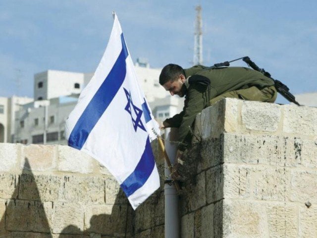 an israeli solider removes the flag from a rooftop in hebron as troops force jewish settlers out of homes they said they had purchased from palestinians photo reuters