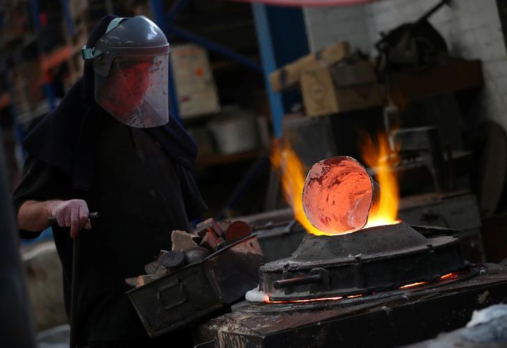 a worker tends to burning bronze during the manufacturing process of a british academy of film and television awards bafta mask at a foundry in west london britain photo reuters