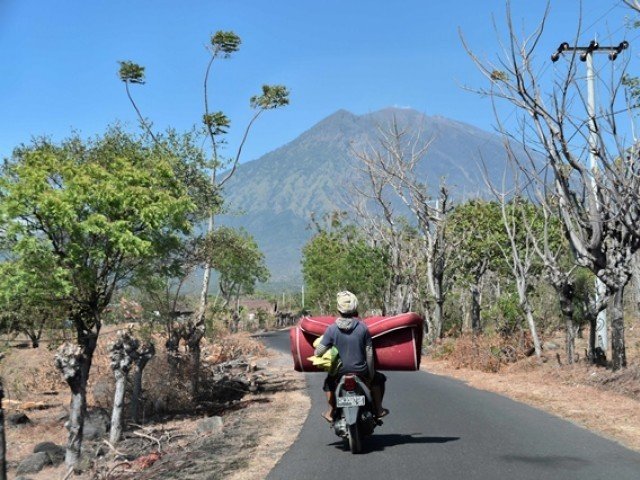 villagers return to their home in kubu village near the base of mount agung volcano in background in karangasem regency on the indonesian resort island of bali photo afp