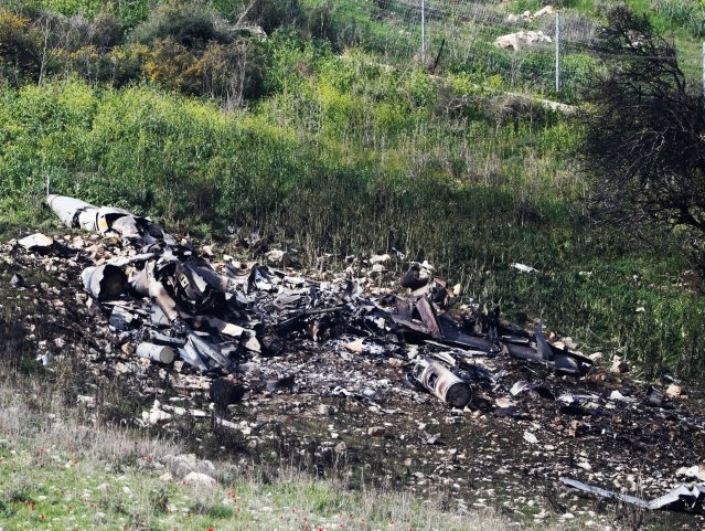 israeli security forces walk next to the remains of an f 16 israeli war plane near the israeli village of harduf israel february 10 2018 photo reuters