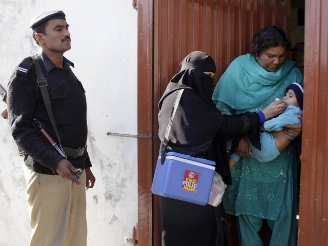 a file photo showing polio worker administering drops while a policeman stands beside her photo express file