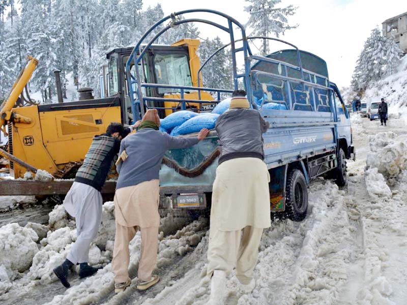 people push a truck stuck in snow after heavy snowfall in galiyat photo agencies