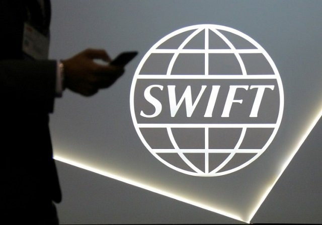 a man using a mobile phone passes the logo of global secure financial messaging services cooperative swift at the sibos banking and financial conference in toronto ontario canada october 19 2017 photo reuters