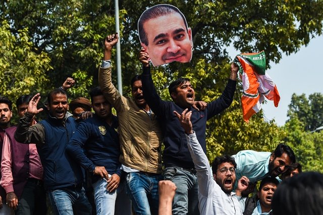 an indian supporters of the congress party keeps his hand on the face of a cut out of billionaire jeweller nirav modi during a protest in new delhi on february 16 2018 indian investigators on february 15 raided the premises of a billionaire jeweller accused of defrauding one of the country 039 s biggest banks photo apf