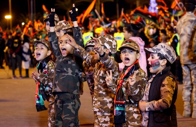 libyan children dressed in camouflage uniforms and wearing scarves bearing the colours of their national flag flash the victory gesture photo afp