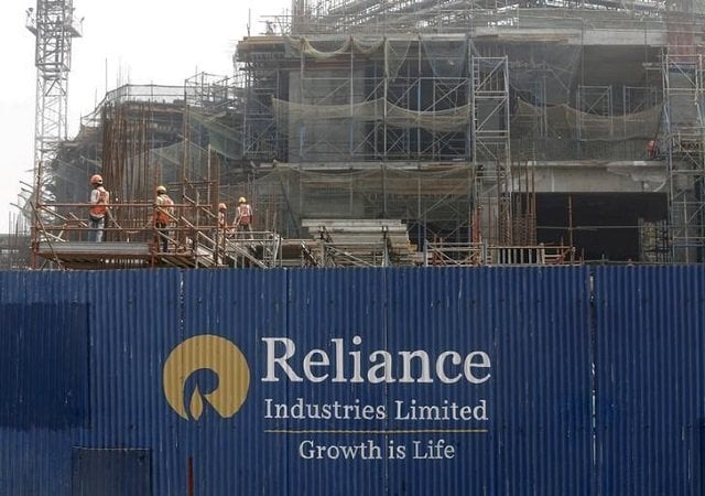 labourers work behind an advertisement of reliance industries limited at a construction site in mumbai india march 2 2016 photo reuters