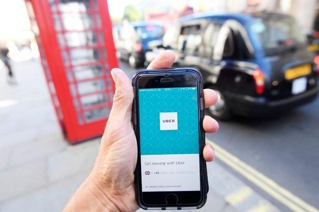 a photo illustration shows a london taxi passing as the uber app logo is displayed on a mobile telephone as it is held up for a posed photograph in central london september 22 2017 photo reuters