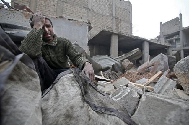 a syrian mourns in the rubble of his home photo afp