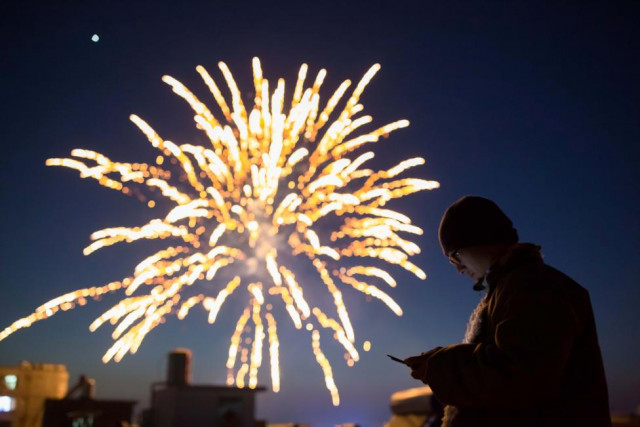 a man looks at his phone as fireworks explode on the eve of the chinese lunar new year or the spring festival in lianyungang jiangsu province china photo reuters a man looks at his phone as fireworks explode on the eve of the chinese lunar new year or the spring festival in lianyungang jiangsu province china photo reuters