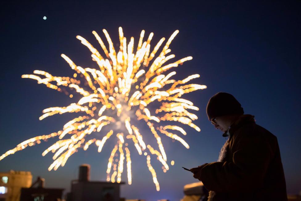 a man looks at his phone as fireworks explode on the eve of the chinese lunar new year or the spring festival in lianyungang jiangsu province china photo reuters