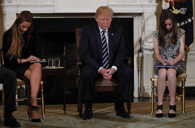 us president donald trump bows his head during a prayer as he sits between marjory stoneman douglas high school shooting survivors and students julia cordover l and carson abt r as the president hosts a listening session with high school students and teachers to discuss school safety at the white house in washington u s february 21 2018 photo reuters