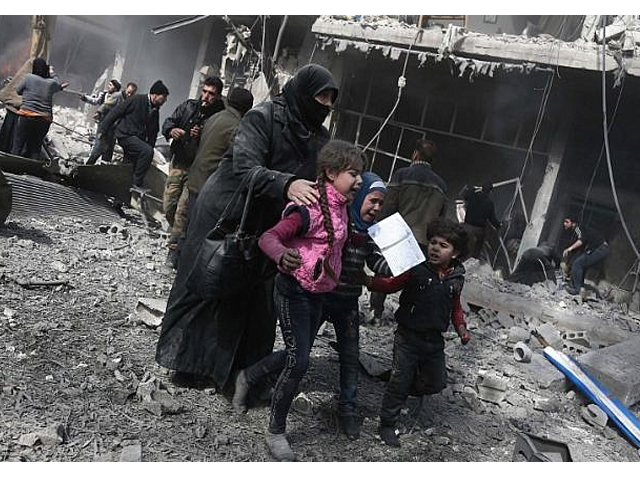 a syrian woman and children run for cover amid the rubble of buildings following government bombing photo afp