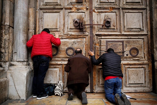 worshippers kneel and pray in front of the closed doors of the church of the holy sepulchre in jerusalem 039 s old city february 25 2018 photo reuters