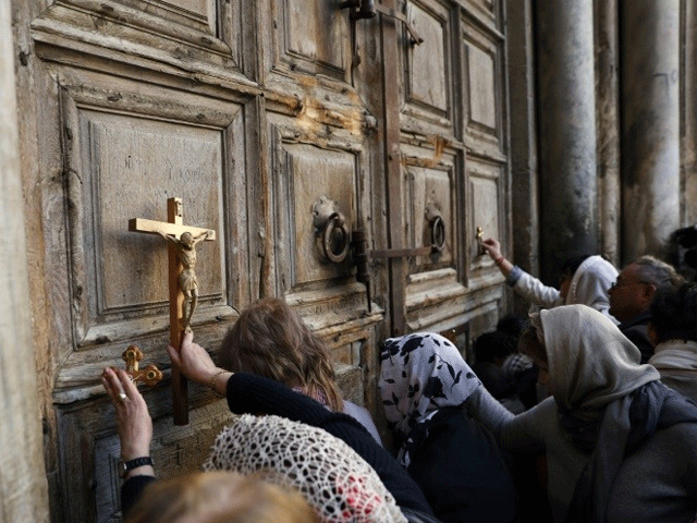 pilgrims pray outside the closed gate of the church of the holy sepulchre in jerusalem 039 s old city on february 27 2018 photo afp