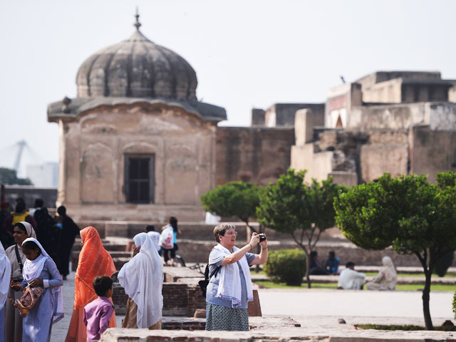 in this photograph taken on october 8 2017 tourists visit the historic mughal era lahore fort in the pakistani city of lahore perched on scaffolding restoration experts chip away at decades of grime and repair broken mosaic tiles that form collossal murals depicting battles and regal ceremonies on the walls of the iconic lahore fort afp photo aamir qureshi