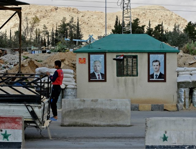 portraits of syrian president bashar al assad r and russian president vladimir putin l hanging outside a guard post at the wafideen checkpoint on the outskirts of damascus neighbouring the rebel held eastern ghouta region photo afp