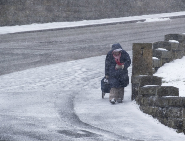 a woman pulls a shopping trolley through a blizzard in the sea side resort of scarborough in north yorkshire uk photo afp