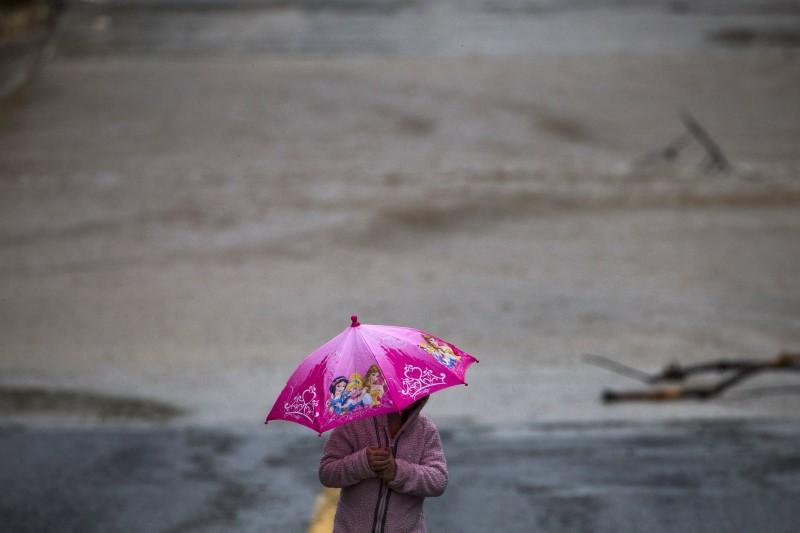 child uses an umbrella to guard against the rain photo reuters