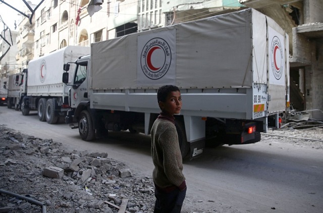 a boy stands as an aid convoy of syrian arab red crescent drives through the besieged town of douma eastern ghouta damascus syria march 5 2018 photo reuters