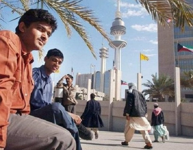 asian workers take a break after work at a park next to kuwait 039 s liberation tower photo afp file