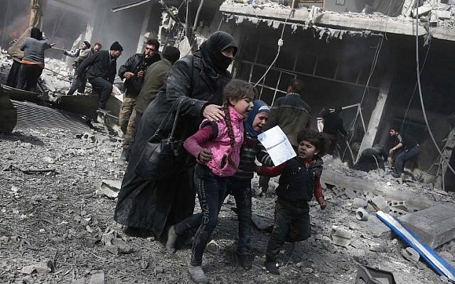 a syrian woman and children run for cover amid the rubble of buildings following government bombing in the rebel held town of hamouria in the besieged eastern ghouta region on the outskirts of the capital damascus photo afp