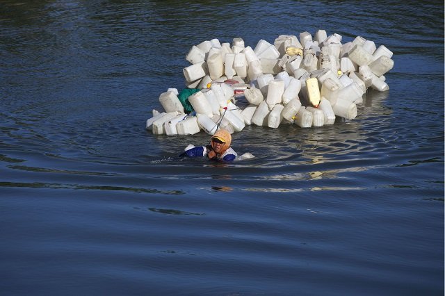 indonesian villager mama hasria swims upstream with about 200 empty jerry cans tied to her back a daily trip she and other local women make to get clean water for their community on sulawesi island photo afp