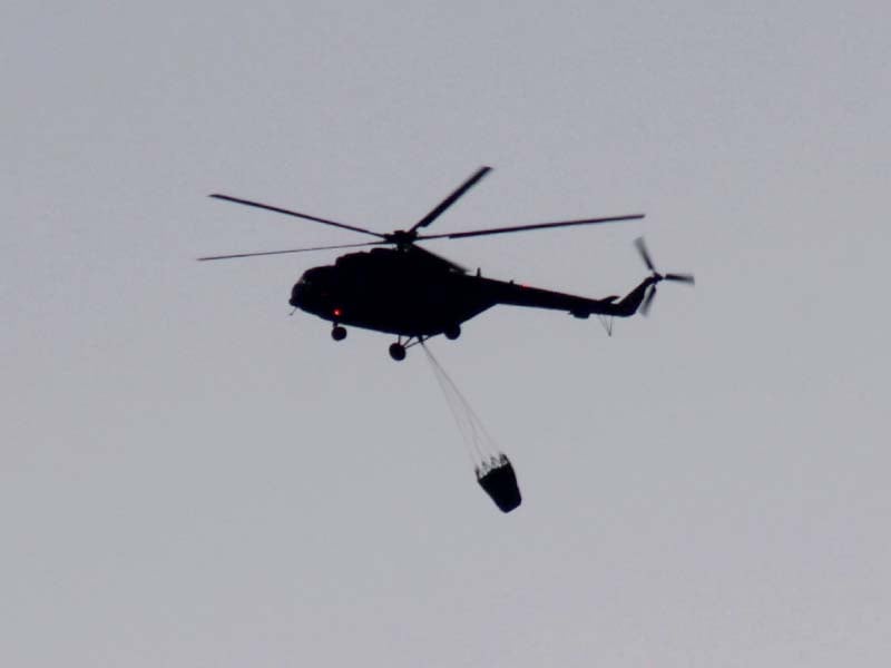 smoke rises from margallas as a helicopter carries huge parachute full of water to douse the flames photo express agencies