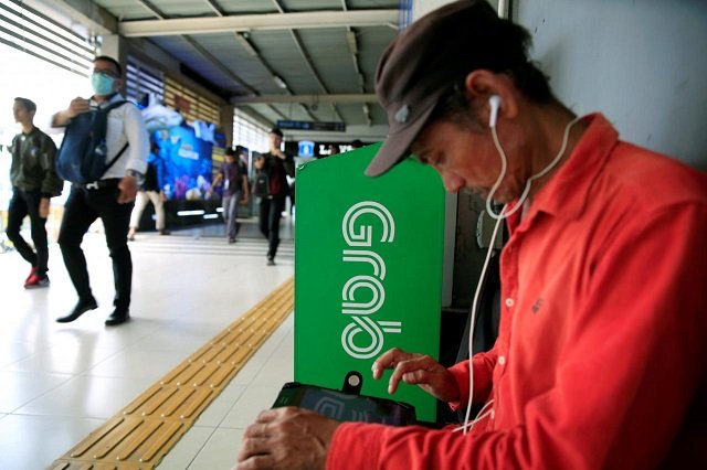 a passenger sits next to grab corner sign as he waits for a grab bike at sudirman train station in jakarta indonesia march 26 2018 photo reuters