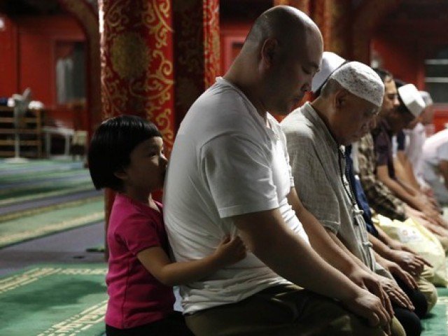 a little girl embraces a muslim man from behind as he prays with other devotees during the evening ramadan prayers on the first day of the fasting month of ramadan at the niujie mosque in beijing photo afp