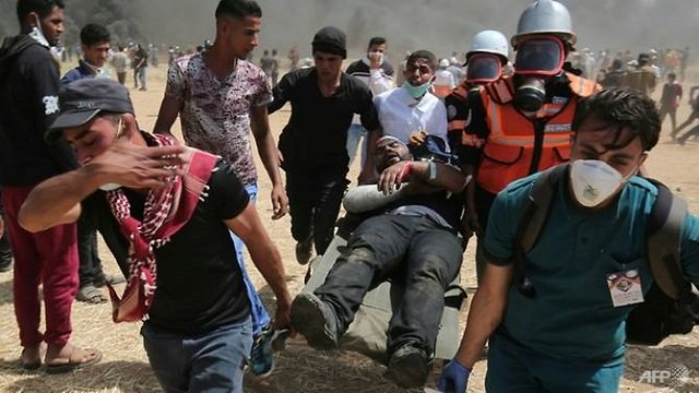 an injured palestinian protester is carried by fellow demonstrators during clashes with israeli security forces near the border with israel east of khan yunis in the southern gaza strip on apr 6 2018 photo afp