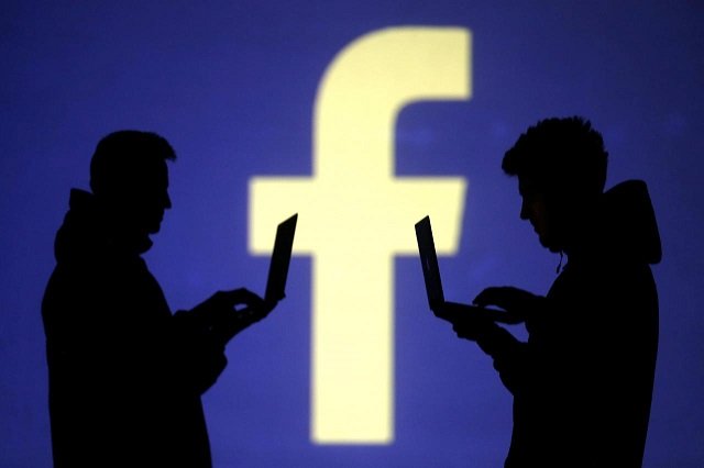 silhouettes of laptop users are seen next to a screen projection of facebook logo in this picture illustration taken march 28 2018 photo reuters