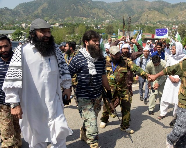 united jihad council ujc leader syed salahuddin l walks with activists and supporters during a protest in muzaffarabad against the recent violence in indian occupied kashmirr on march 7 2018 photo afp