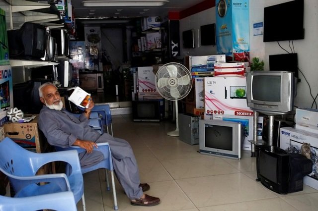 a man uses a piece of paper to fan himself during a power outage at a shop selling television sets in karachi pakistan april 12 2018 photo reuters