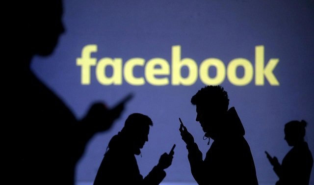 silhouettes of mobile users are seen next to a screen projection of facebook logo in this picture illustration taken march 28 2018 photo reuters